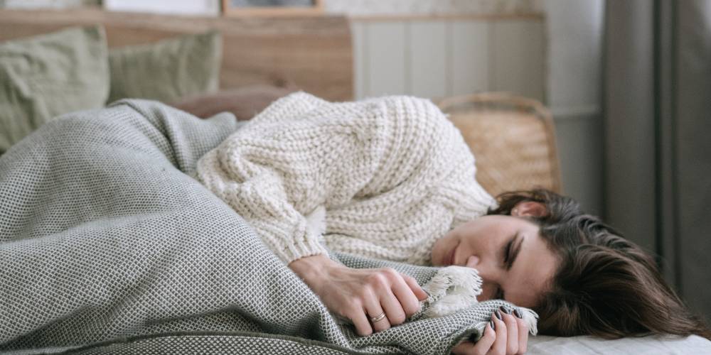 woman with chronic pain and depression lying down wearing a white jumper