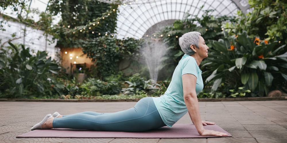 elderly woman doing yoga living with chronic back pain