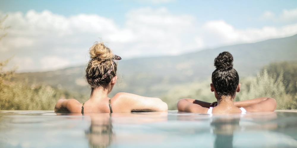 2 women sitting in pool discussing fibromyalgia